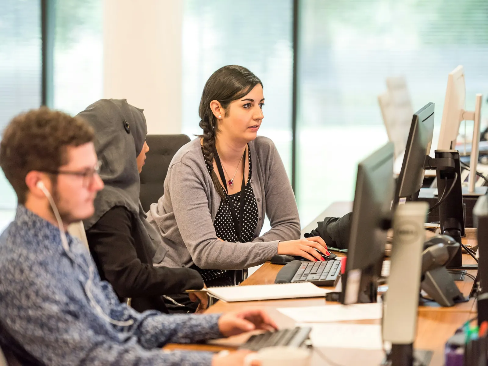 Agents with headsets working at their screens in a bright contact centre