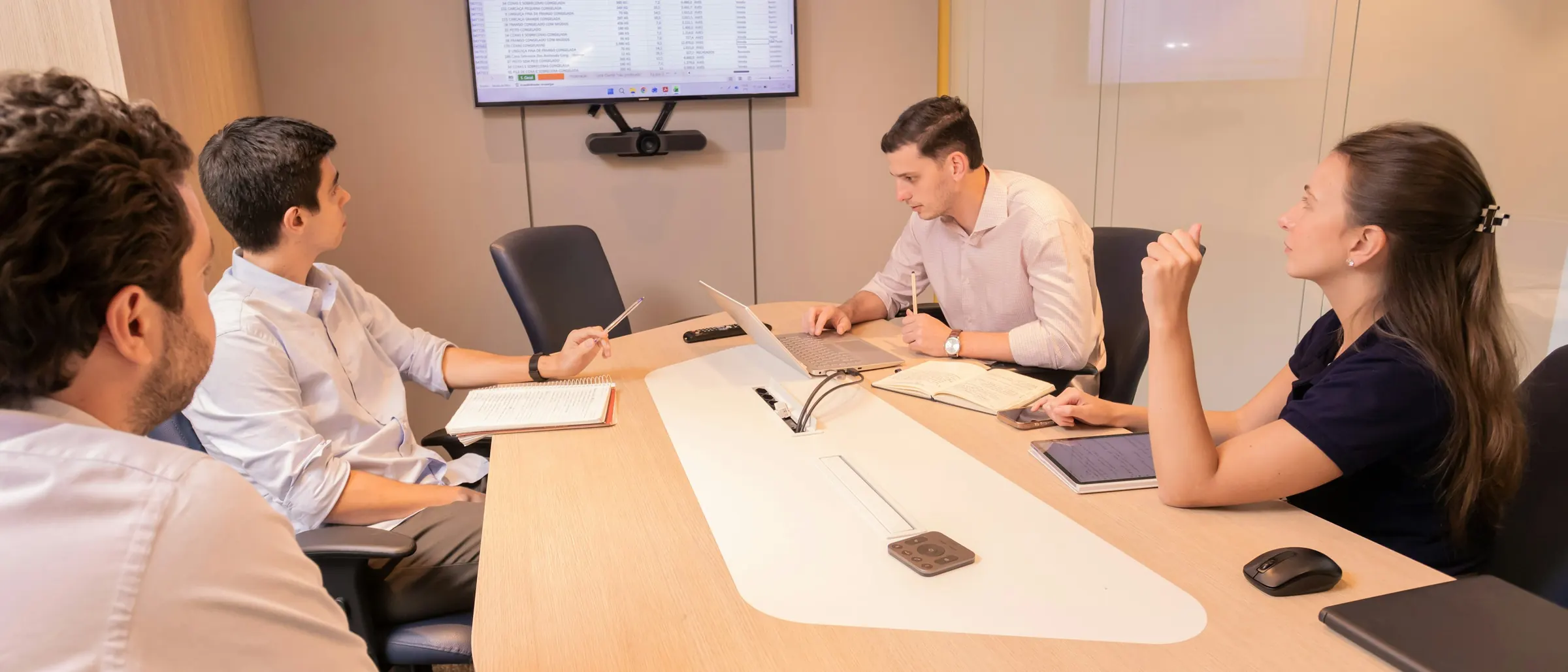 Team discussing work around a conference table with a display on the wall
